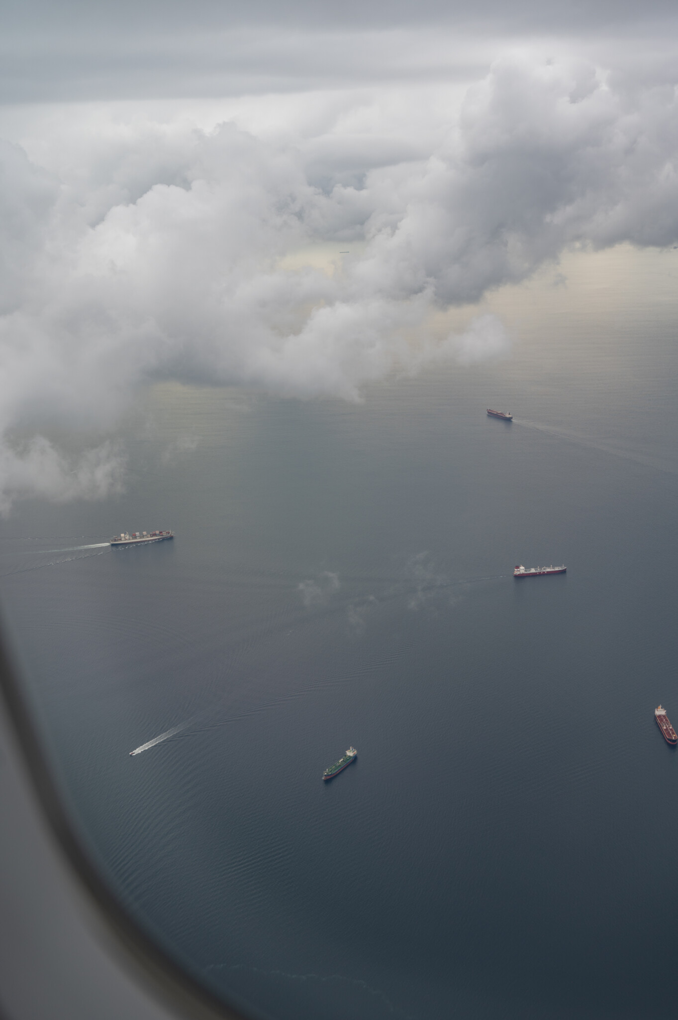 Blick aus dem Flugzeugfenster auf Schiffe im Meer